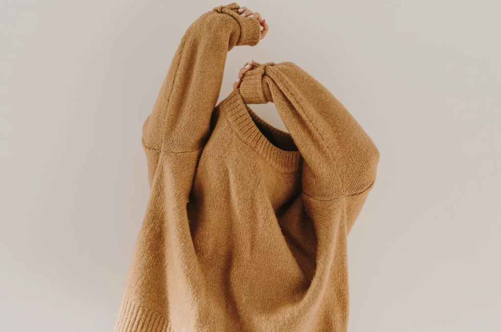 Frau zieht Pullover über den Kopf