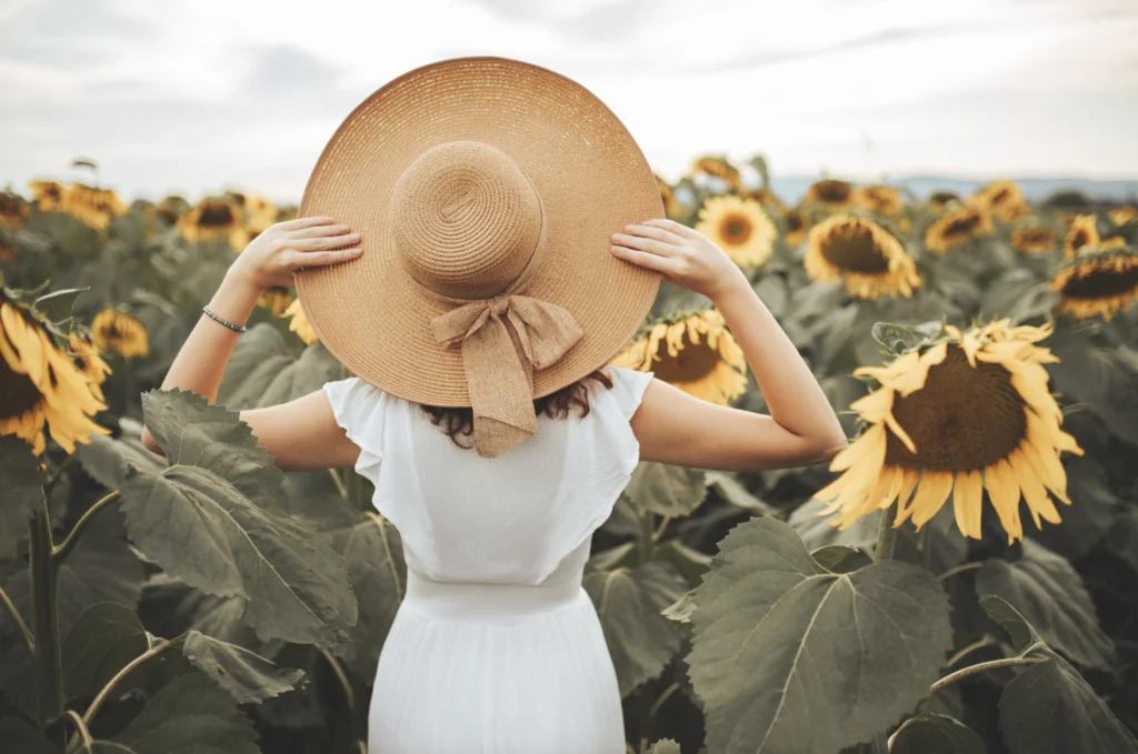 Frau mit Hut im Sonnenblumenfeld